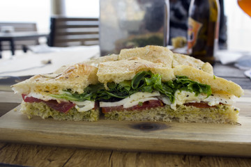 Sandwich with italian bread, lettuce, tomato,cheese and pesto sauce 
