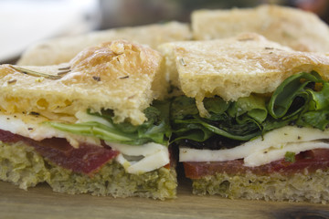Sandwich with italian bread, lettuce, tomato,cheese and pesto sauce 