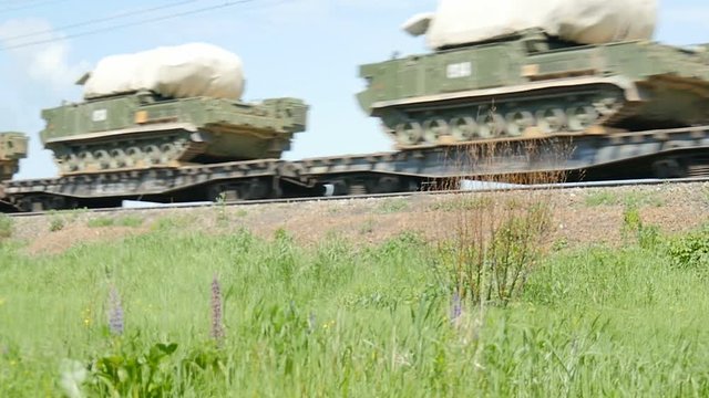 Military equipment is transported on platforms by rail.