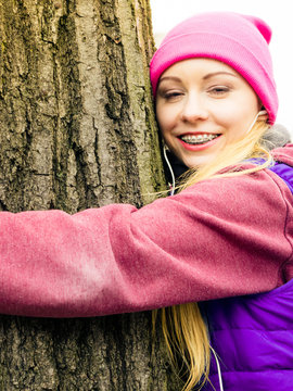 Woman wearing sportswear hugging tree
