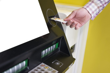 Naklejka premium Hand of a man with a credit card, using an ATM. Man using an atm machine with his credit card.