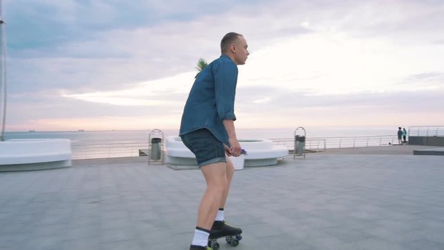 a young caucasian man roller skating with quad skates near the sea