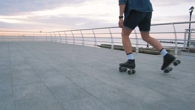 a young caucasian man roller skating with quad skates near the sea, slow motion