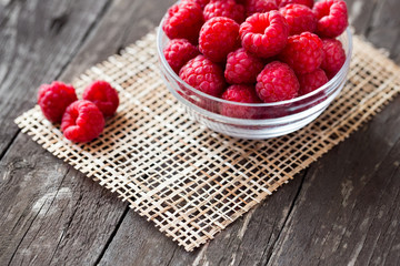 Sweet fresh raspberry in bowl on wood.