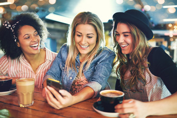 Three young girlfriends relaxing over coffee