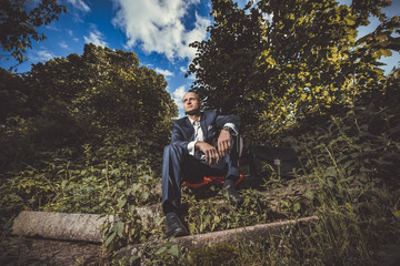 Serious man sitting on a old broken stairs