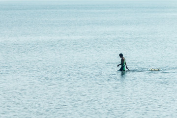 Alone fisherman passing through the shallow sea.