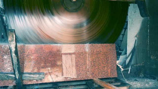 Bridge Saw Machine in stone-working plant sawing red granite block