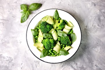 Healthy salad of broccoli, green peas, cucumber and avocado with basil and olive oil. Healthy food. Top view, copy space.