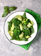 Healthy salad of broccoli, green peas, cucumber and avocado with basil and olive oil. Healthy food. Top view, copy space.
