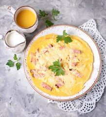 Scrambled eggs with ham and cheese on a gray textured background. Top view. Copy space.