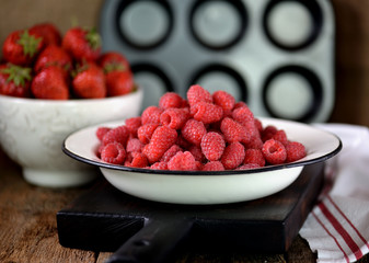 Healthy breakfast is fresh organic raspberries, strawberries with oat flakes and milk on an old wooden background. Rustic style.