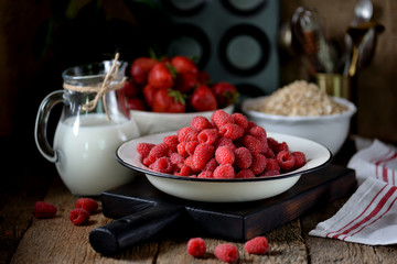 Healthy breakfast is fresh organic raspberries, strawberries with oat flakes and milk on an old wooden background. Rustic style.