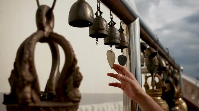 Woman touching sacral bells in Wat Saket Ratcha Wora Maha Wihan (the Golden Mount). Bangkok Thailand.