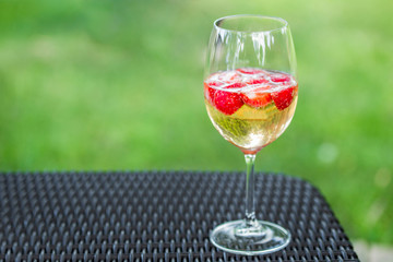 Glass of champagne with strawberries on a table outdoors. Rossini cocktail