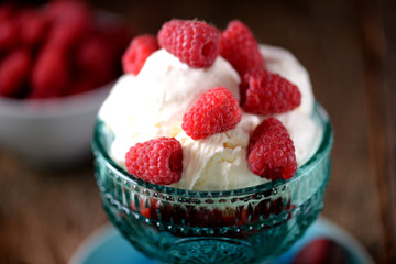 Homemade organic ice cream with fresh raspberries on an old wooden background.