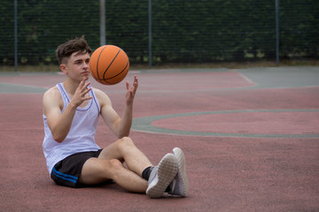 Naklejka premium Teenage boy tossing a basketball from one hand to another on a court