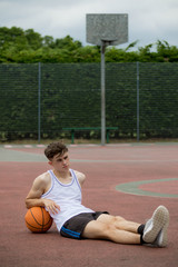 Teenage boy sitting on a  basketball court