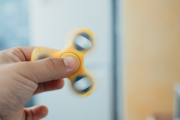 Yellow fidget spinner in male hand, selective focus