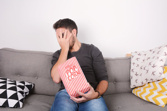 Man eating popcorn and watching movies.