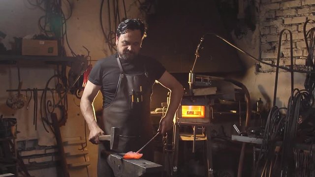 blacksmith works with metal on anvil in forge. Slow motion