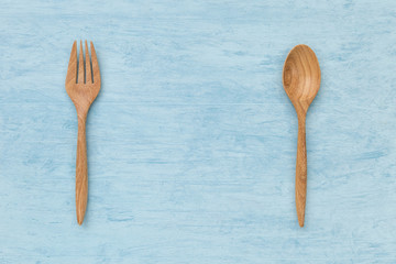 Natural wood texture of fork and spoon with space on blue texture background