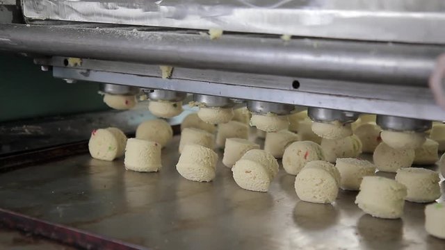 Industry of confectionery products biscuit at baking factory. Equipment makes cookies, dough pieces laid out on sheet, cut with iron wire. Cottage cheese pastry with candied fruits, send further bake