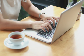 Concentrated at work. Confident young woman in smart casual wear working on laptop while sitting near window in creative office or cafe