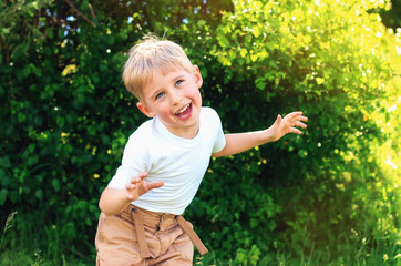 Baby boy playing in park with happy smiling face and blond hair showing tongue and making face,