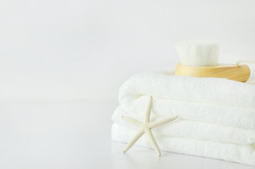 Fototapeta na wymiar Starfish and white towels with Facial cleansing brush