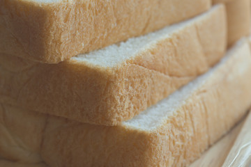 Sliced bread stack on wood plate close up concept. Soft and sticky homemade bread for delicious toast in breakfast. Homemade bakery background with copy space in sliced bread concept.