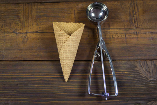 Cornet and spoon for ice cream on wooden background