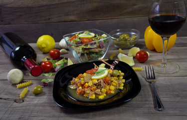 Milanez salat with fresh vegetable, olives, lemon, tomato, papper, garlik, mushrooms and wine in background. Mediterian food