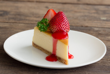 Homemade New York cheesecake on white plate decorated by strawberry,parsley and strawberry sauce. Moist and smooth classic baked cheesecake. Copy space background of delicious New York cheesecake.