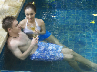 Man and woman drinking champagne in the pool