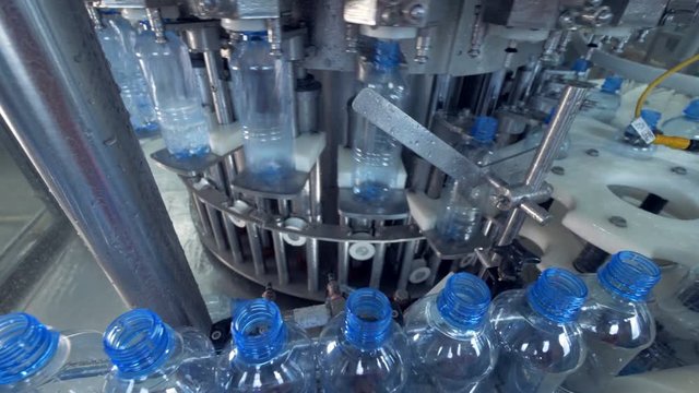 Water bottles lifted up to an automatic filler. 