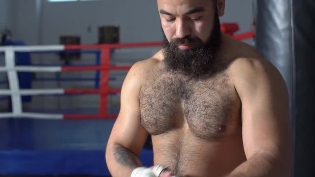 Boxer putting on punching wraps in fitness studio