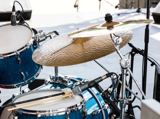 blue drum set with two wooden drumsticks on it. musical instruments on stage, ready for the gig.