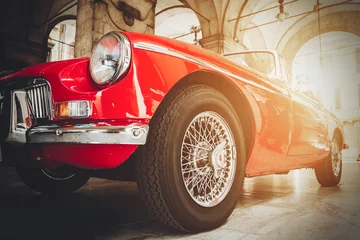 Rolgordijnen Vooraanzicht van rode glanzende klassieke vintage auto. Retro getinte ansichtkaart, poster. © mykolastock