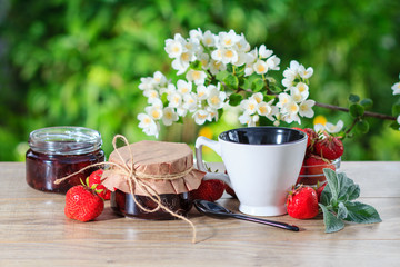 Traditional homemade strawberry jam in a jars, decorated with fresh strawberries and jasmine