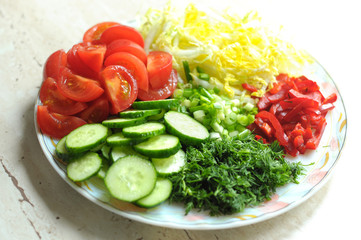 Fresh organic sliced vegetables on the white plate on the wooden table. Close up, selective focus.