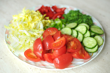 Fresh organic sliced vegetables on the white plate on the wooden table. Close up, selective focus.