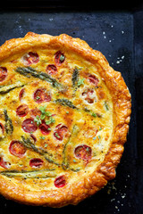  Quiche with cherry tomatoes and green asparagus on a black background