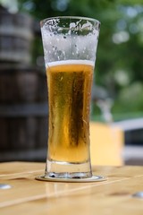 Glass full of beer with white foam on wooden table