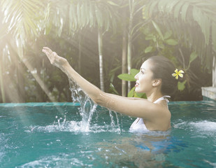 Woman playing with water in the swimming pool