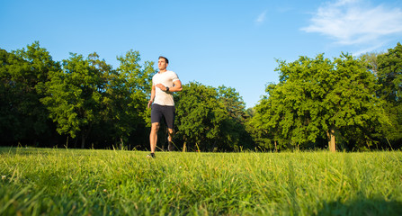 A handsome young man running during sunset in a park