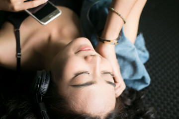 young beautiful woman lying down listening music headphones with her smartphone
