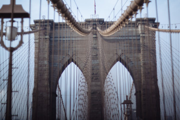 Closeup of Brooklyn Bridge's brick tower and steel suspension cables; antique lamp at left