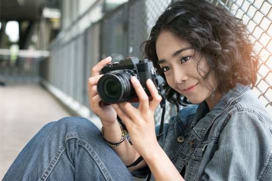 .Portrait of a young woman holding camera in hand taking pictures on street walk shopping mall background.