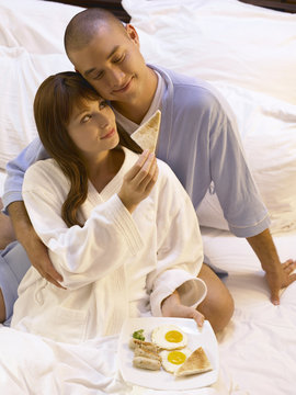 Couple Sharing Breakfast On The Bed